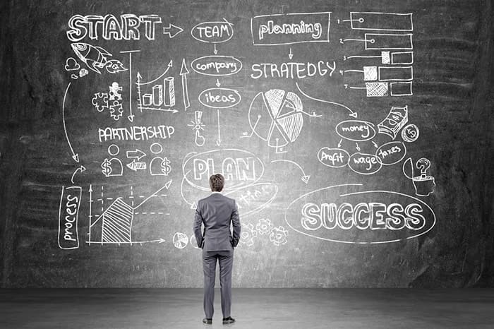 businessman looking at plan on blackboard