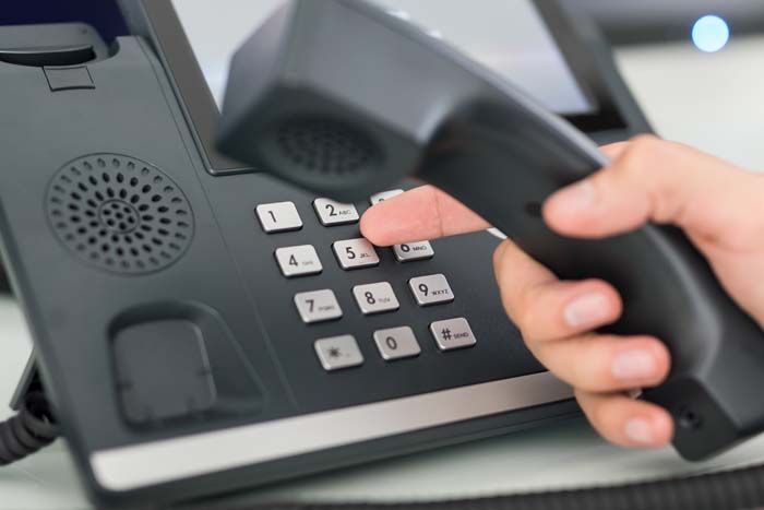 Fingers dialing a number on a deskphone