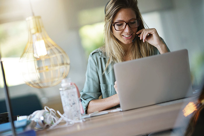 An image of a woman using best practices in her work from home call center.